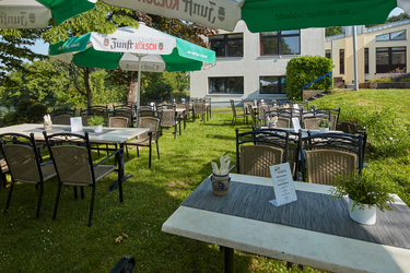 Tische im Freien auf einer Wiese mit Sonnenschirmen