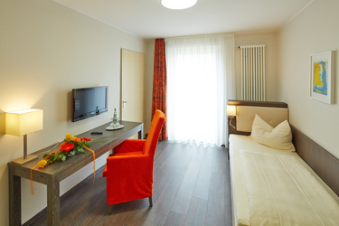 Einzelzimmer mit Bett ,Fernseher und Tisch mit Stuhl