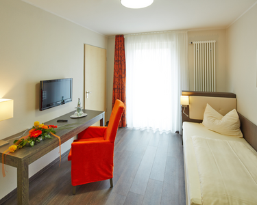 Einzelzimmer mit Bett ,Fernseher und Tisch mit Stuhl